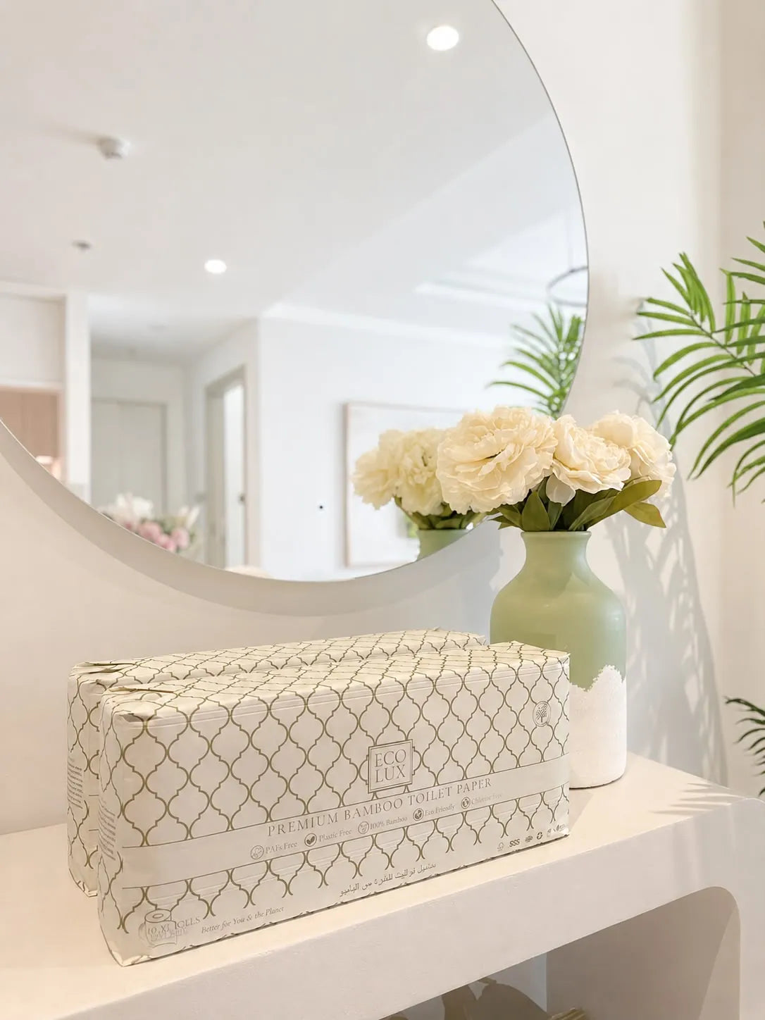 An Eco Lux case on a white vanity beside a round mirror and white roses