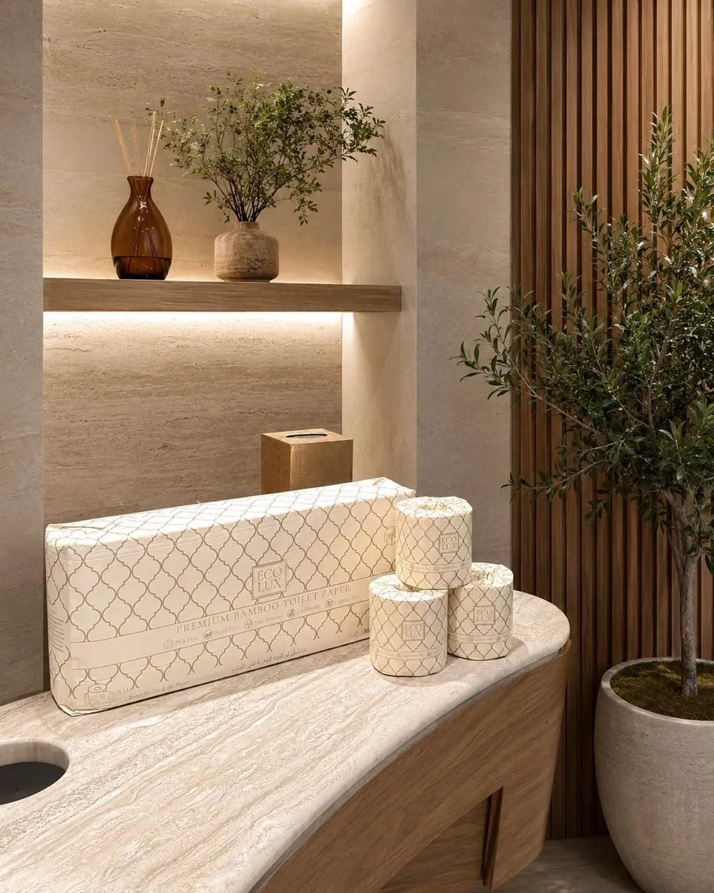 An Eco Lux case and three rolls on a curved stone vanity in a warm spa bathroom