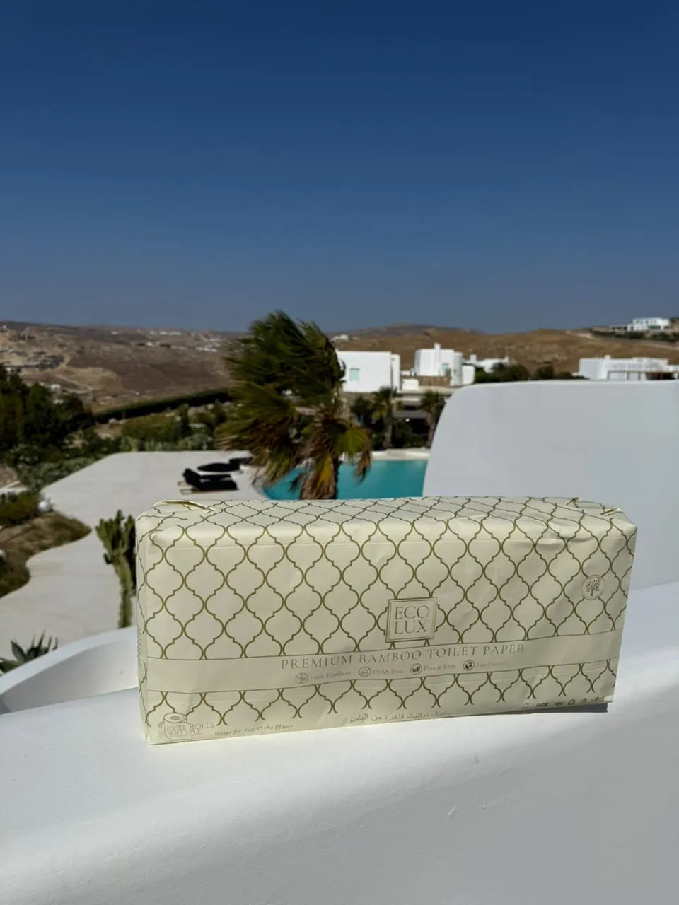 An Eco Lux case on a white terrace wall with hills and whitewashed houses in the distance