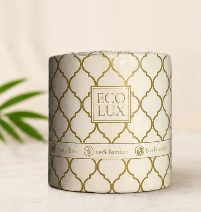 A wrapped Eco Lux roll with its gold ogee print and a bamboo leaf beside it