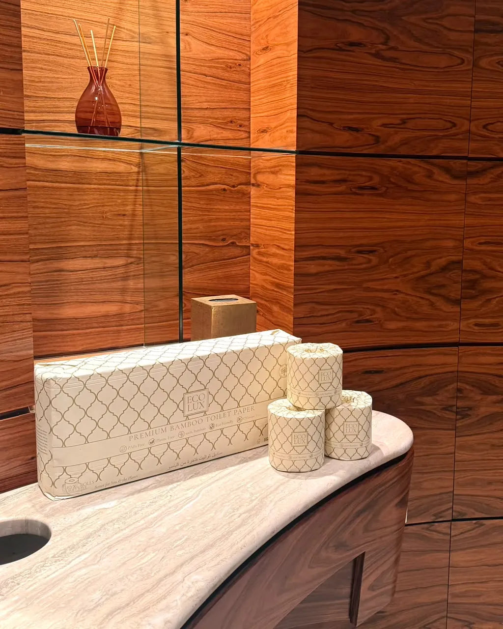 An Eco Lux case and two rolls on a marble basin against walnut panelling